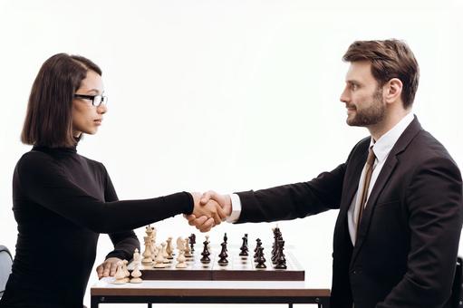 チェスの上で握手をする男女(白背景) チェスの上で握手をする男女(白背景)の写真