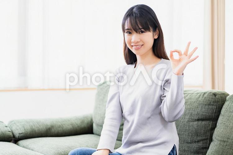 リビングのソファでOKのジェスチャーをする若い女性 女性,成功,okの写真素材