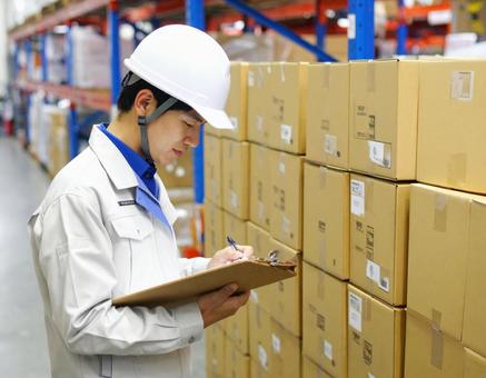 倉庫で在庫をチェックする男性作業員 倉庫で在庫をチェックする男性作業員の写真
