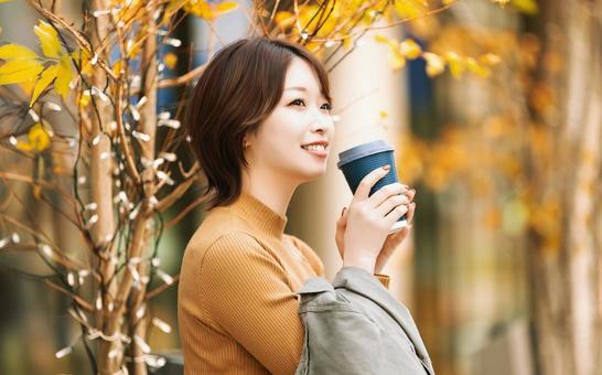 秋の屋外で暖かい飲み物を飲む女性 秋の屋外で暖かい飲み物を飲む女性 女性,秋,笑顔の写真素材