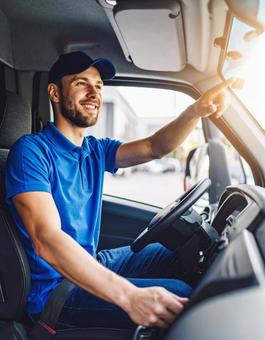 笑顔で運転する若い配達ドライバー 笑顔で運転する若い配達ドライバーの写真