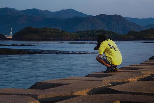 <Material> A boy taking a photo of the sea at dusk from the embankment, JPG