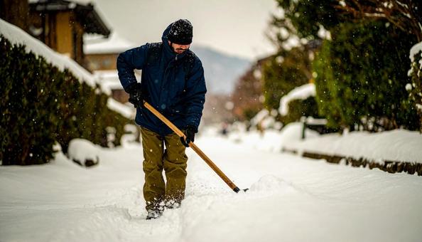 大雪が降った日の翌日の朝に雪かきする男性 大雪が降った日の翌日の朝に雪かきする男性の写真