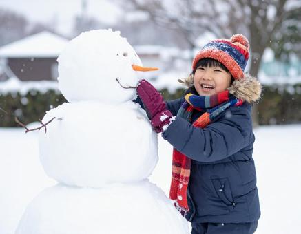 雪だるまを作って喜ぶ子供の冬の屋外風景の写真