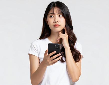 スマホを持ち考える主婦 スマホを持ち考える主婦の写真