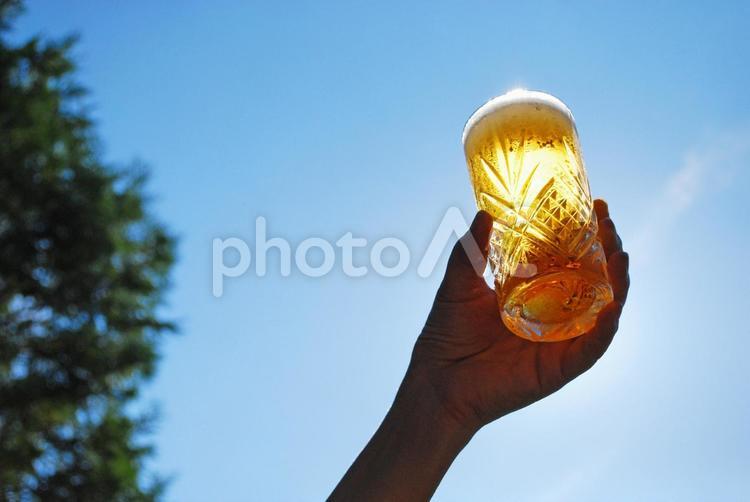 夏の屋外でビールを持つ女性の手　逆光 青空,ビール,夏の写真素材