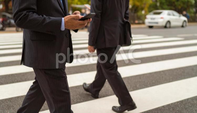 歩きながら携帯を見るビジネスマン 横断歩道,ながらスマホ,20代の写真素材