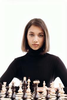 チェスをしている黒いタートルネックのカメラ目線の女性(白背景) チェスをしている黒いタートルネックのカメラ目線の女性(白背景) チェス,女性,20代の写真素材