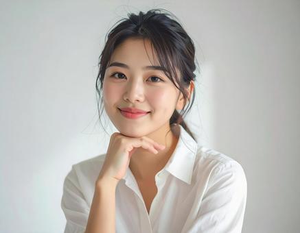 笑顔で頬杖をつく若い女性 笑顔で頬杖をつく若い女性の写真