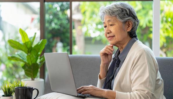 パソコンを使う日本人シニア女性の横顔 パソコンを使う日本人シニア女性の横顔の写真