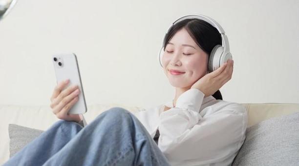 ワイヤレスヘッドフォンで音楽を聞く女性 ワイヤレスヘッドフォンで音楽を聞く女性の写真