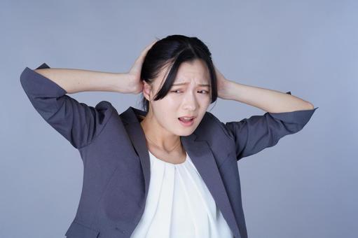 頭を抱えたスーツ姿の女性 女性,頭を抱える,困るの写真素材