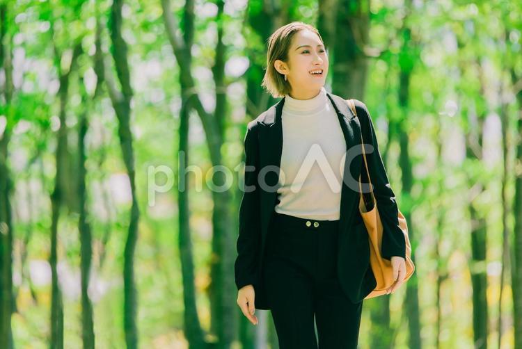 緑の中を歩く笑顔のビジネスウーマン 女性,笑顔,春の写真素材