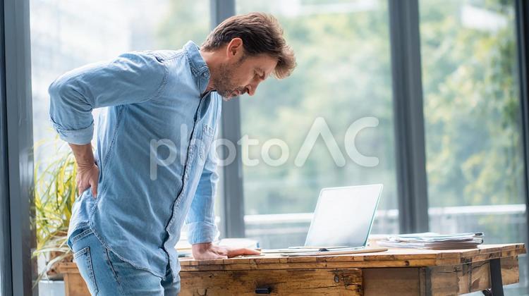 オフィスで腰に痛みを感じる男性 男性,腰痛,痛みの写真素材