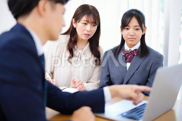 家庭訪問でノートパソコンを指さし話す教師 塾,人物,女の子の写真素材