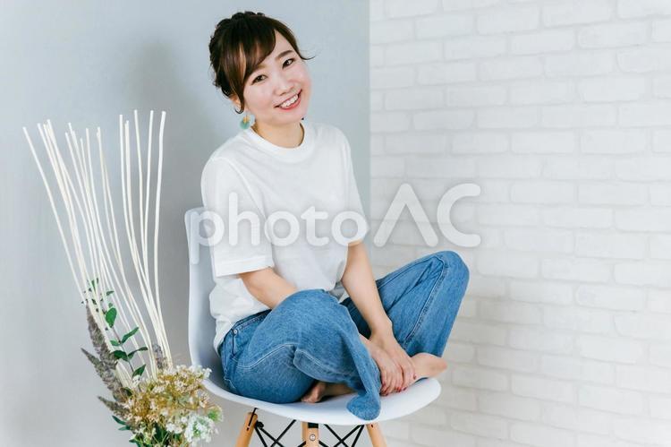 椅子の上で胡坐をかくジーンズ姿の女性 女性,デニム,新生活の写真素材