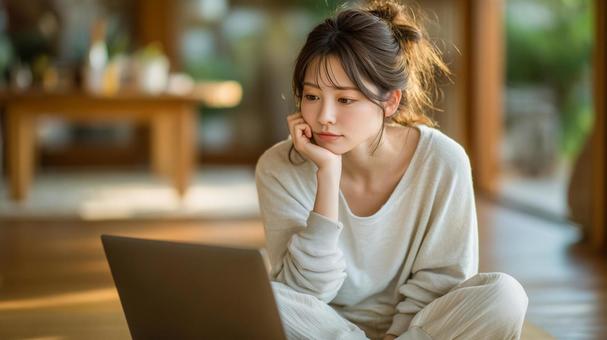 部屋着でパソコンを見る女性の写真