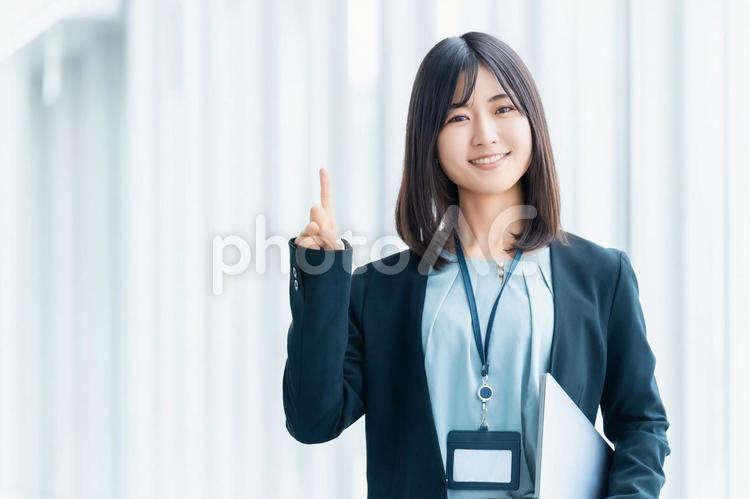 パソコンを持って案内をする笑顔の女性 女性,パソコン,指の写真素材