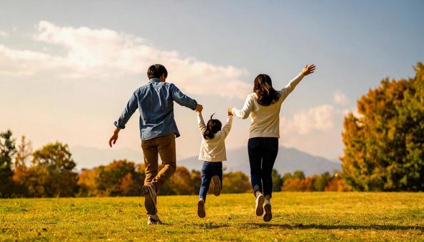 秋晴れの草原でジャンプする家族の写真