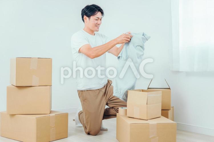 段ボールから洋服を出す男性 ダンボール,引越し,荷物の写真素材