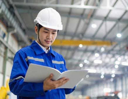 製造現場で真剣に確認作業を行う男性技術者の写真