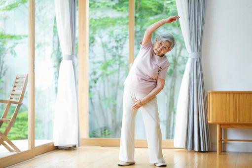 窓際で手を伸ばし体操する高齢女性 女性,体操,伸ばすの写真素材