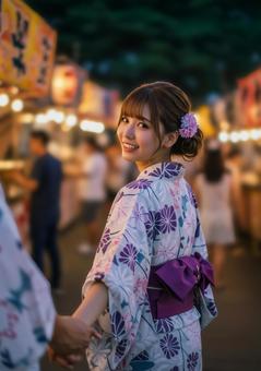 夏祭りで浴衣姿の女性が手を引き振り返る姿 夏祭りで浴衣姿の女性が手を引き振り返る姿の写真