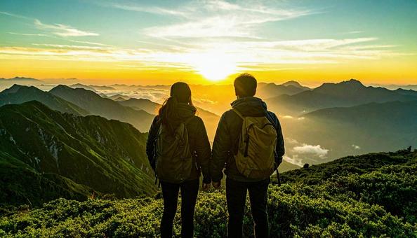 山から朝日を眺める日本人カップル 山から朝日を眺める日本人カップルの写真