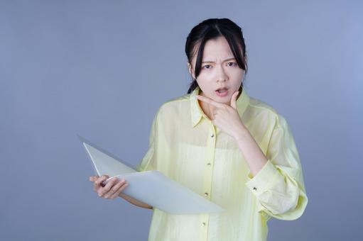 資料を見てしかめっ面の黄色い服の女性 女性,バインダー,ファイルの写真素材