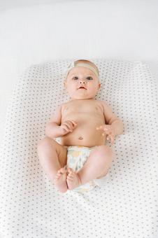 カメラ目線で笑う仰向けでオムツ姿の赤ちゃん 赤ちゃん,かわいい,仰向けの写真素材