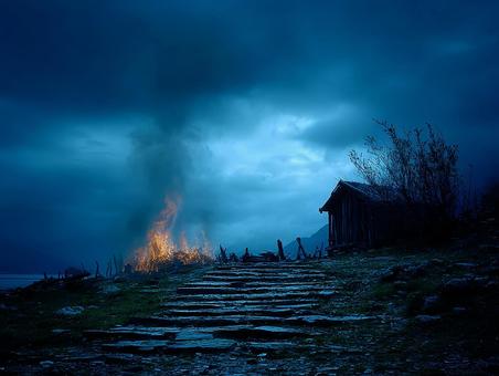 闇夜に燃える古い家の写真