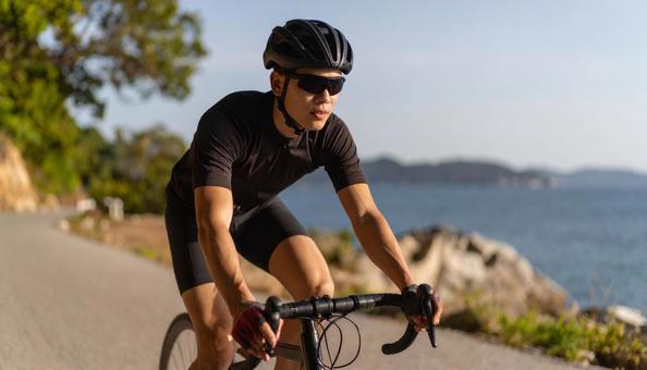 休日に海辺をサイクリングする男性 休日に海辺をサイクリングする男性の写真