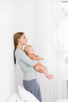 壁に寄り掛かり赤ちゃんを抱く母 壁に寄り掛かり赤ちゃんを抱く母 女性,赤ちゃん,かわいいの写真素材