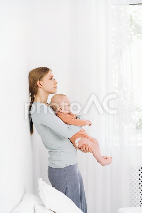壁に寄り掛かり赤ちゃんを抱く母 女性,赤ちゃん,かわいいの写真素材
