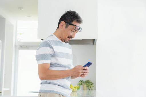 キッチンでスマホを使うミドルの男性 キッチンでスマホを使うミドルの男性 男性,スマホ,ミドルの写真素材