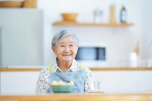 穏やかに微笑み座るエプロンの高齢女性 女性,リンゴ,フルーツの写真素材