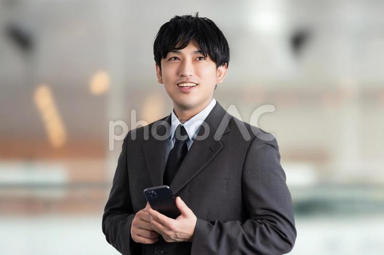 スマホを持つ笑顔の男性ビジネスマン 男性,ビジネス,ビジネスマンの写真素材