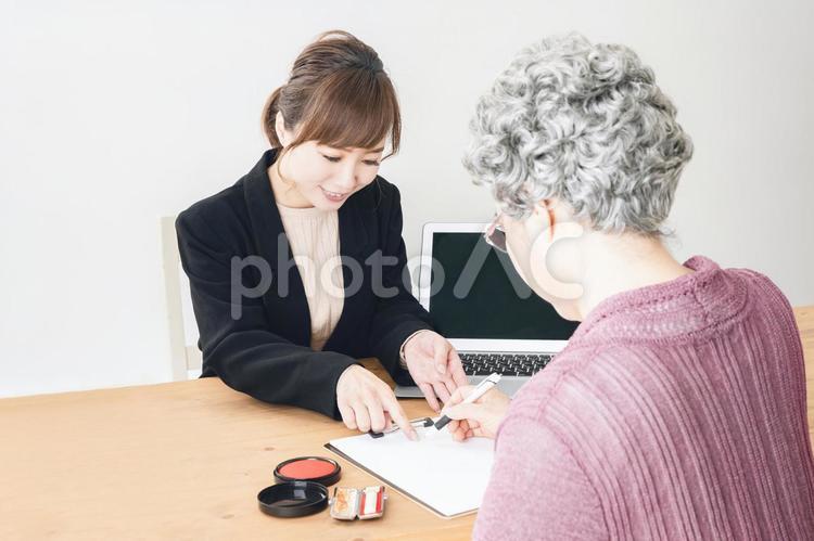 スーツ姿の女性と書類にサインする高齢者 高齢者,終活,遺言書の写真素材