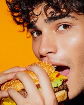 若い男性がハンバーガーを楽しむ瞬間 若い男性がハンバーガーを楽しむ瞬間の写真
