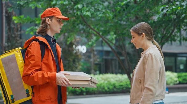 屋外で女性客にピザを渡す配達員 配達,フードデリバリー,デリバリーの写真素材