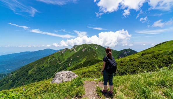 山登りで山頂で深呼吸する女性の後ろ姿 山登りで山頂で深呼吸する女性の後ろ姿の写真
