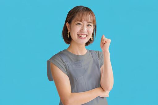 ガッツポーズするエプロンの女性 若者,笑顔,ガッツポーズの写真素材