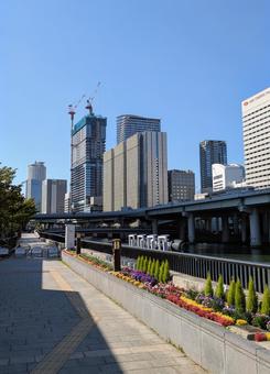 建設中の高層ビルと川沿いの花壇　青空 都市,高層ビル,街並みの写真素材