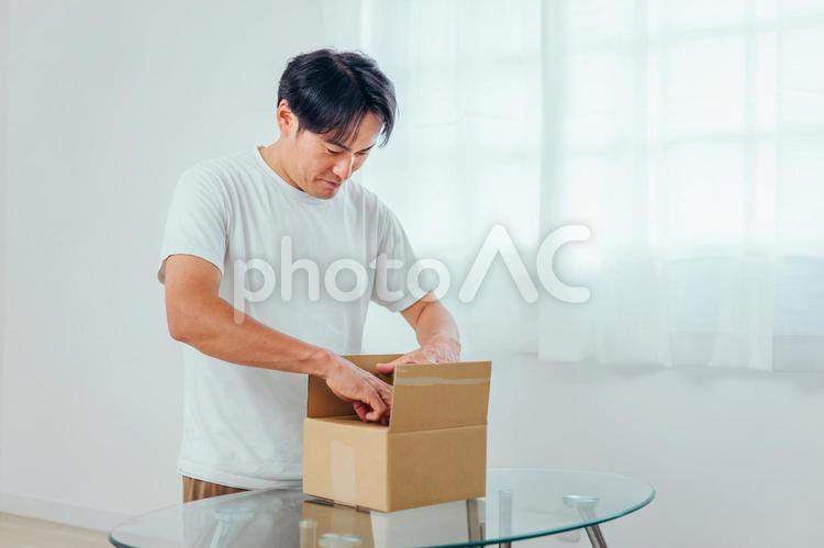 段ボールを開ける男性（喜ぶ） 荷造り,宅急便,宅配便の写真素材