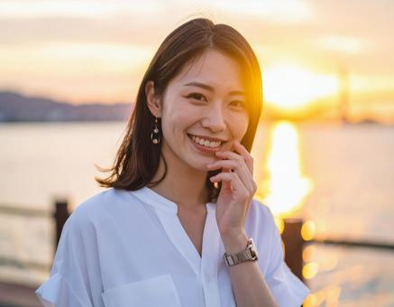 夕陽に照らされる女性の微笑み 夕陽に照らされる女性の微笑みの写真