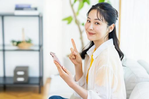 部屋でスマホを操作する女性 部屋でスマホを操作する女性 スマホ,笑顔,部屋の写真素材