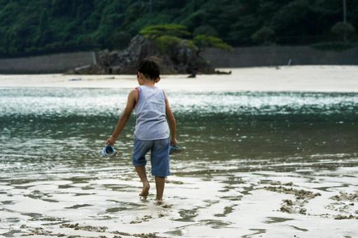 <素材>夕暮れの海で水遊びをする男の子 <素材>夕暮れの海で水遊びをする男の子の写真