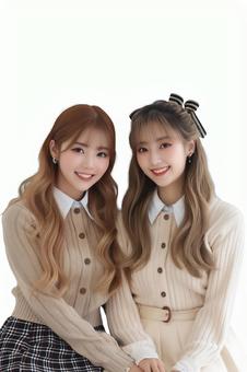 笑顔で寄り添う女子学生の秋冬ファッションの写真