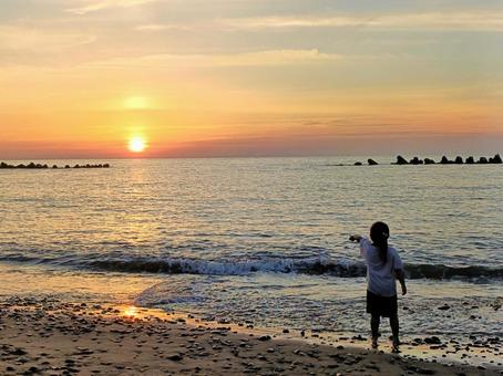 沈む夕陽を指差す女の子 沈む夕陽を指差す女の子 日本海,海,夕陽の写真素材