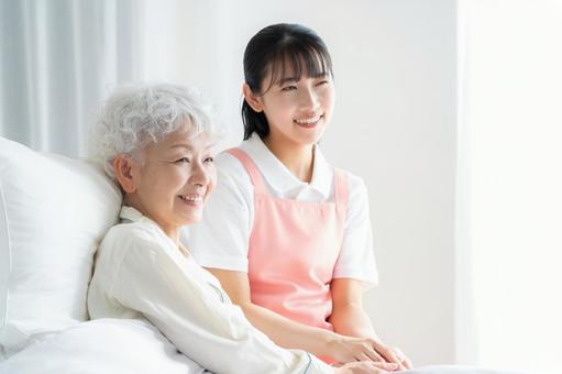 寝ているシニア女性を介護をする介護士 寝ているシニア女性を介護をする介護士 介護,介護士,シニアの写真素材